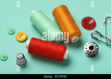 Composition with thread spools, thimble and buttons on mint background, closeup Stock Photo