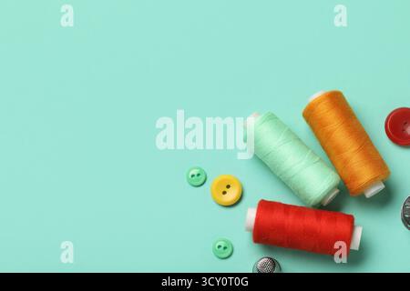 Composition with thread spools and buttons on mint background, closeup Stock Photo