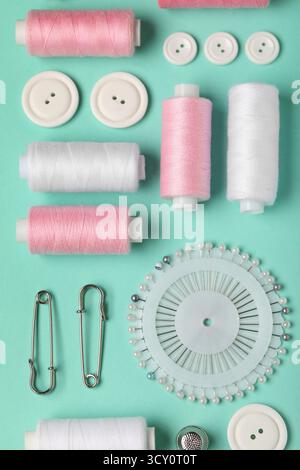 Composition with thread spools, ball pins and buttons on mint background, closeup Stock Photo