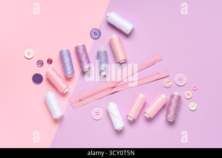Thread spools with buttons and zipper on color background Stock Photo