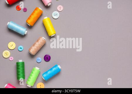 Different thread spools and buttons on grey background Stock Photo