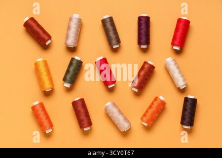 Many different thread spools on orange background Stock Photo