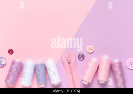 Thread spools with buttons and zipper on color background Stock Photo