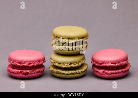 Three colorful macarons arranged in a row on gray background. Bright pastel colors and simple layout for bakery or dessert promotion. Stock Photo
