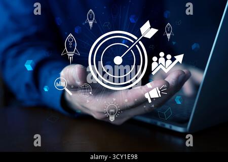 Businessman presenting a digital target icon with rocket, graph, innovation symbols, representing goal achievement, business growth, marketing strateg Stock Photo