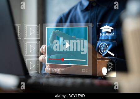 E-learning and online education concept showing a person using a laptop with virtual video player interface, study icons, and digital training visuals Stock Photo