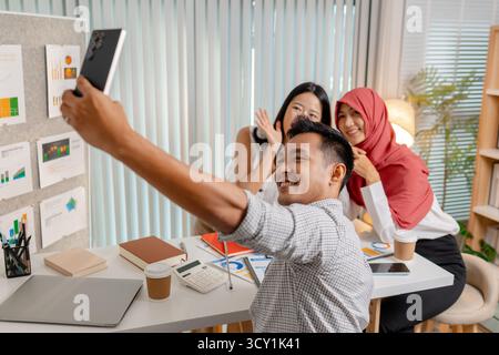 A cheerful team of diverse coworkers taking a selfie together in a modern office after a successful meeting, capturing a moment of happiness and teamw Stock Photo