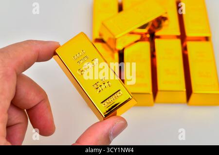 Close up Hand holding gold bar isolated on white background Stock Photo