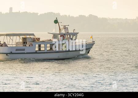 Small boat on a quiet lake near the coast with parasol and flag, boat trip, Lake Constance, Germany Stock Photo