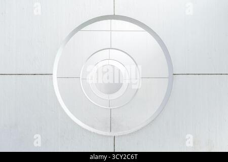 Striking minimalist architectural detail featuring white concentric circles and intersecting lines, creating an optical tunnel effect Stock Photo