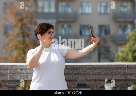 A middle-aged woman records videos on her phone, blogger, video call Stock Photo