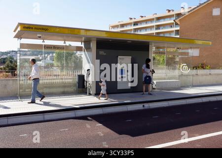 People waiting at a yellow-roofed Metro Mondego bus stop on a sunny day with tall apartment buildings in the background, Coimbra, Portugal, Europe Stock Photo