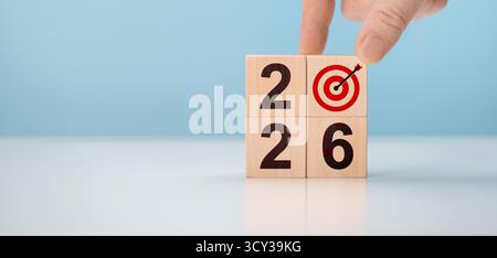 Hand creating 2026 new year business plan with wooden blocks. Man placing dartboard icon to form year number concept Stock Photo