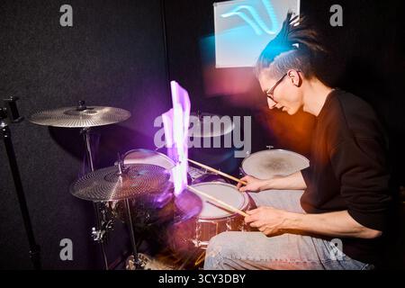 Drummer performing in a studio with vibrant lighting effects Stock Photo