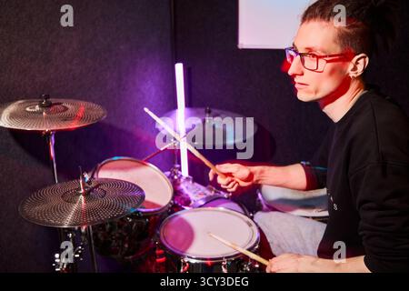 Energetic drummer performing in a studio with colorful lights Stock Photo