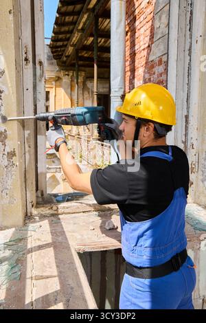 Construction worker using a drill in an old building renovation Stock Photo