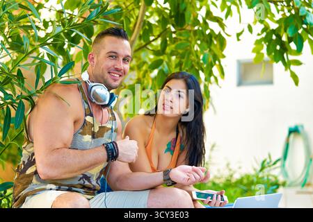 smiling couple in garden with technical leisure devices Stock Photo