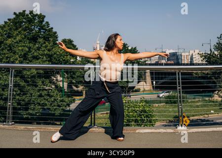 Female dancer performing urban contemporary movement on bridge Stock Photo