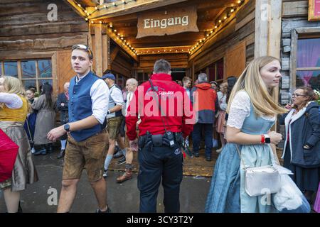 Visitors in traditional traditional costume leaving a wooden entrance at the Oktoberfest while security is present, Volksfest Cannstatter Wasen, Sonja Stock Photo