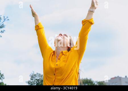 Happy young woman outdoors raising arms celebrating freedom and success Stock Photo