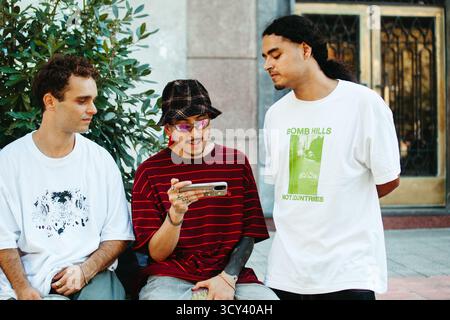 Multiethnic group of skaters sharing a moment while watching a video outdoors Stock Photo