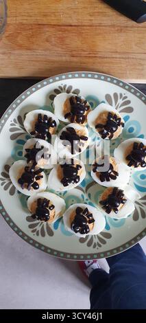 Deviled eggs decorated with black olive spiders for a Halloween party, mobile photo. Fun and spooky homemade snack perfect for seasonal food, celebrat Stock Photo