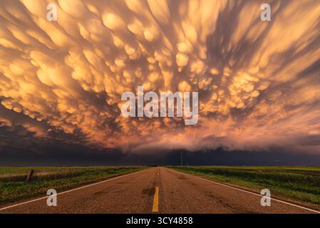 Incredible sunset mammatus clouds glow with vivid colors after a tornado outbreak in Kansas, showcasing dramatic skies, storm aftermath, vibrant light Stock Photo