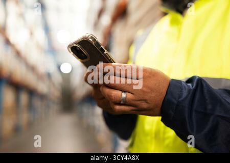 Man, hands and typing with phone in warehouse for communication, networking or social media. Closeup of male person or employee on mobile smartphone Stock Photo