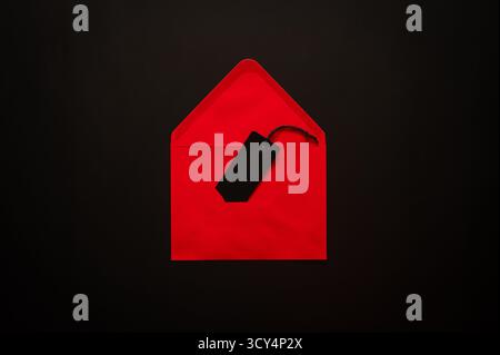 Black Friday concept with an open red envelope holds a black price tag on a dark background for signaling a secret sale. Stock Photo
