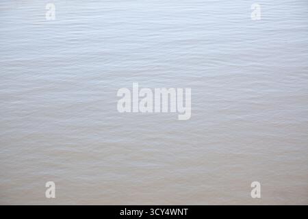 The surface of the river reflects a smooth and gentle texture, with light ripples moving slowly. The scene captures the essence of tranquility on a su Stock Photo