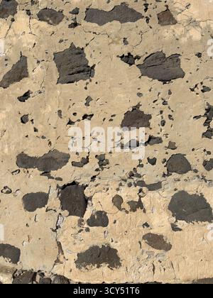Close-up of aged stucco wall showing rough volcanic stones and cracked surface details Stock Photo