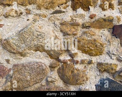 Rough stone wall displaying a textured pattern, ideal for backgrounds Stock Photo