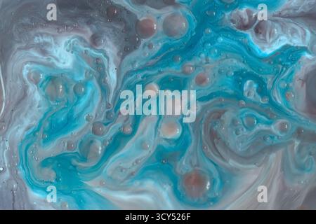 Macro shot of swirling blue, teal, and beige liquid patterns with scattered bubbles. Smooth, dynamic marbling texture, artistic and organic Stock Photo