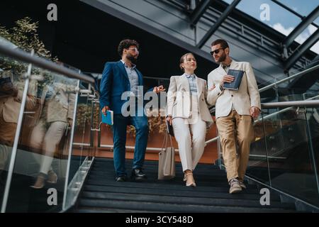 Three business professionals walking down stairs in a modern building Stock Photo
