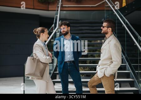 Three professionals having a casual conversation outdoors near a staircase Stock Photo