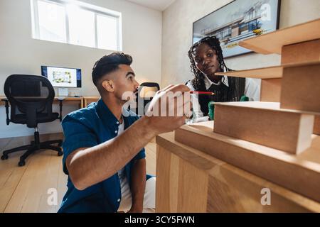 Two architects working closely on a scale model, engaging in discussion and planning. Stock Photo