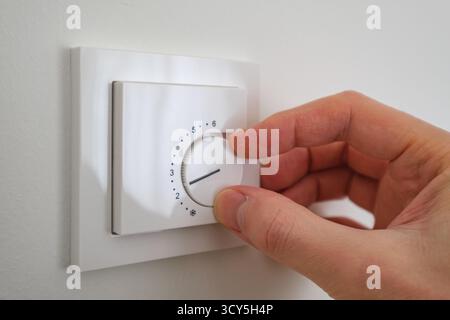 Hand adjusting the indoor heater setting, close up shot Stock Photo