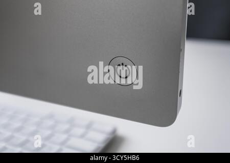Power button on an Apple iMac computer with the keyboard on a desk in the background Stock Photo
