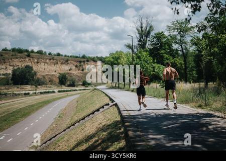 Two people jogging on a scenic path during a sunny day outdoors Stock Photo