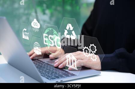 ESG environmental social governance investment business concept. Businessman use a laptop computer to analyze ESG data. icons pop up on virtual screen Stock Photo