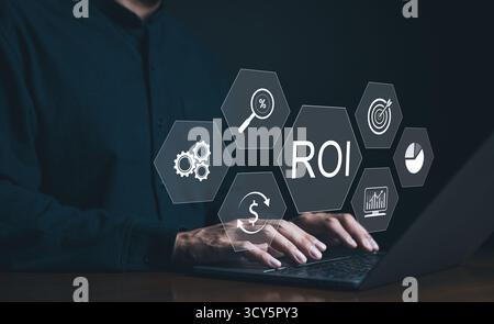 Analyzing Return on Investment ROI on Laptop. A businessman is using a laptop with graphics representing ROI analysis, including financial growth Stock Photo