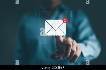 New email notification interaction concept. A person interacting with a floating digital interface showing a new email notification symbol, a concept Stock Photo