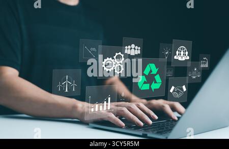 Sustainable development planning concept. Person using a laptop with virtual icons related to recycling, renewable energy, and environmental Stock Photo