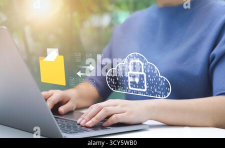 Person Managing Secure Cloud Data Transfer. An individual uses laptop to manage secure data transfer to cloud, virtual lock, Stock Photo