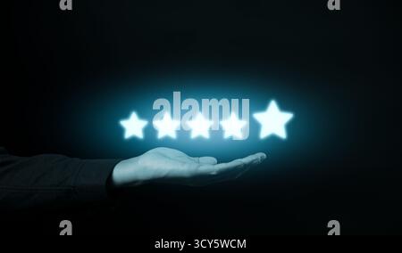 Five-Star Customer Review Satisfaction Concept. Hand presenting glowing five-star icons against a dark background, symbolizing customer review, Stock Photo