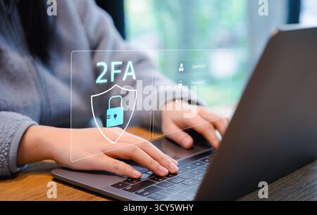 Two-Factor Authentication for Cyber Security. Person using a laptop with a digital screen displaying a shield icon and "2FA" representing two-factor Stock Photo