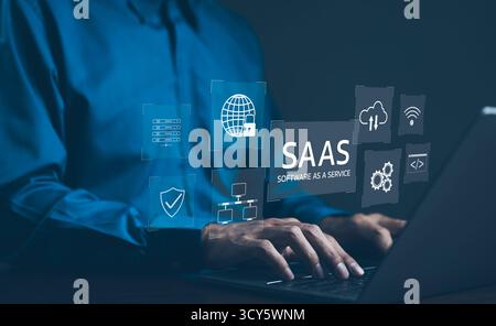SaaS Concept, Software as a Service, A man types on laptop with digital icons representing various aspects of Software as a Service (SaaS) Stock Photo