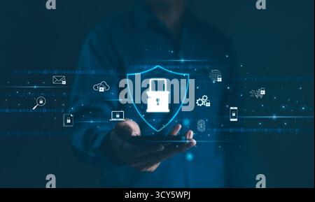Cybersecurity Concept. A person holds a smartphone displaying a shield with a lock symbol, surrounded by various cyber security icons, Stock Photo