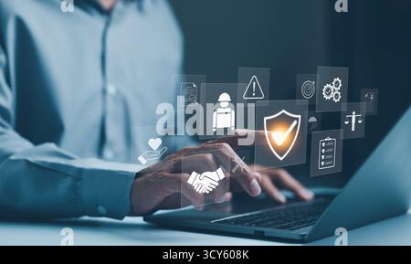 Work safety and compliance concepts. Businessman typing on laptop with virtual icons representing work safety, compliance, and security, workplace Stock Photo