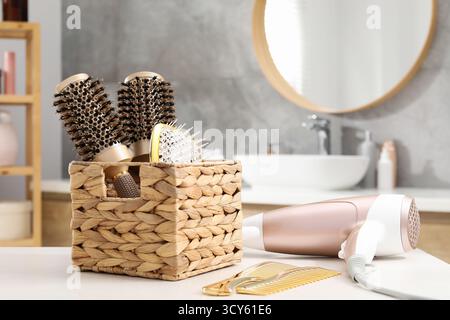Different hair styling tools on white table in bathroom, closeup Stock Photo